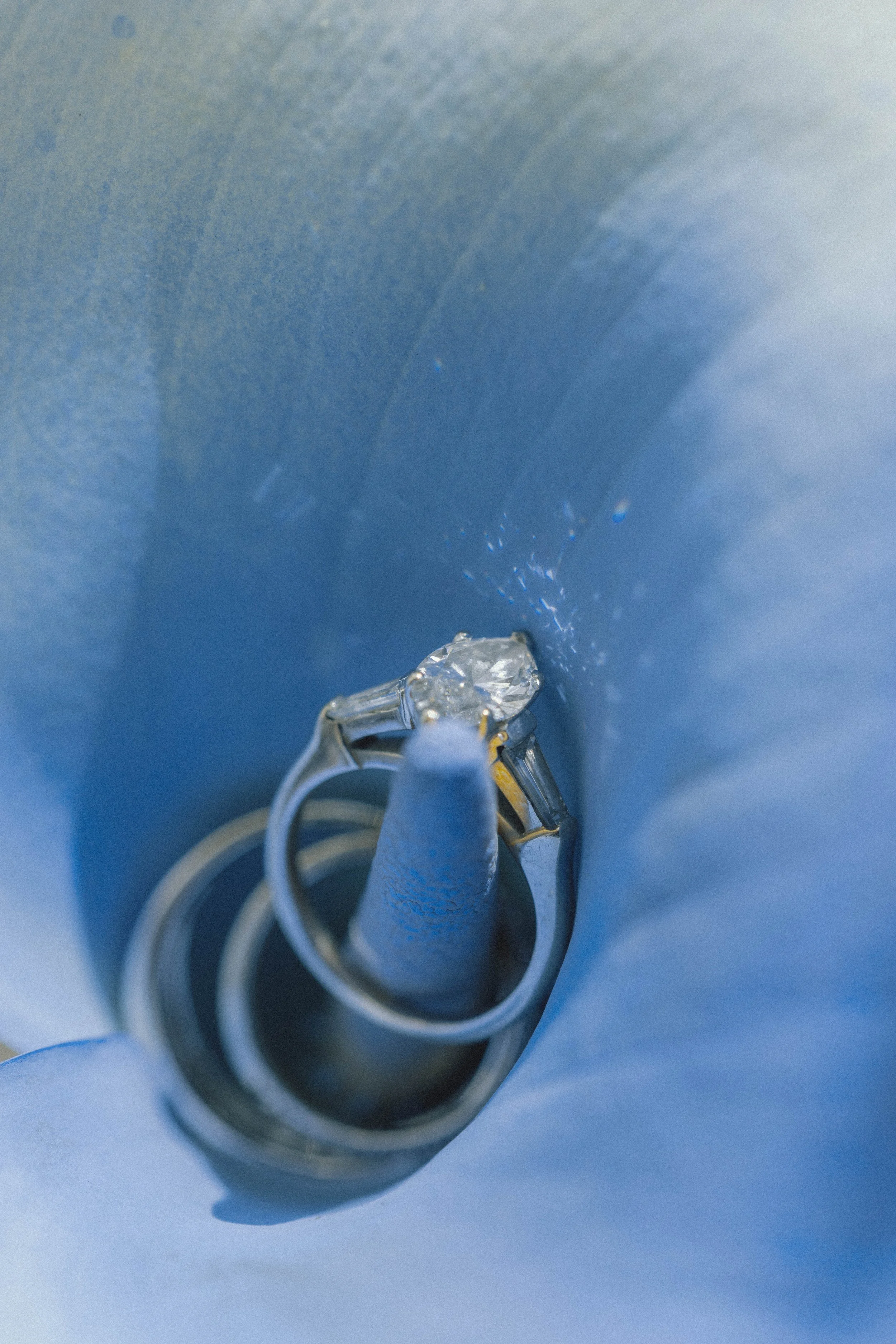 Close-up of a small, clear, and shiny diamond ring on a blue background.