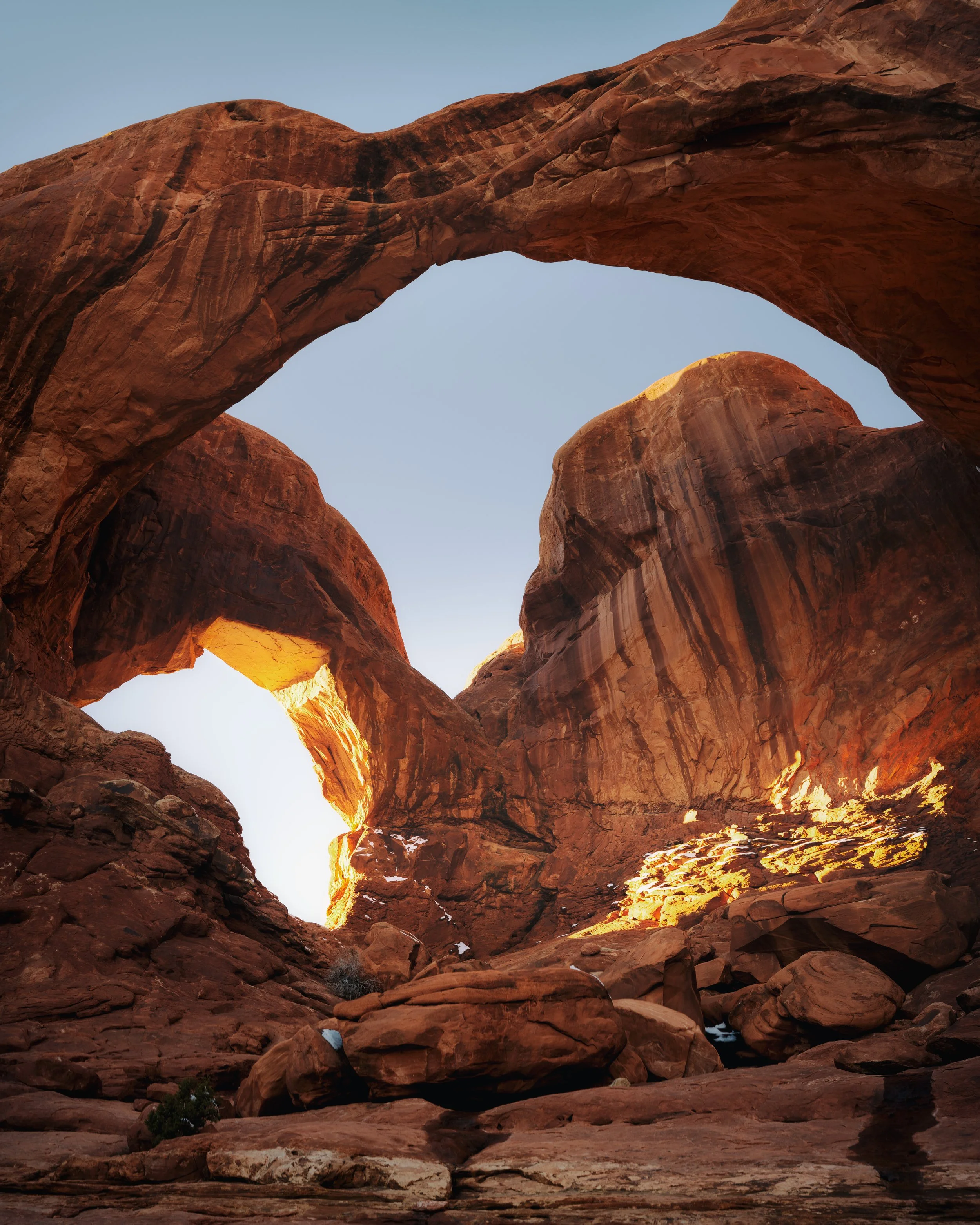 Red rock formations and natural arches in a desert landscape, with blue sky overhead.