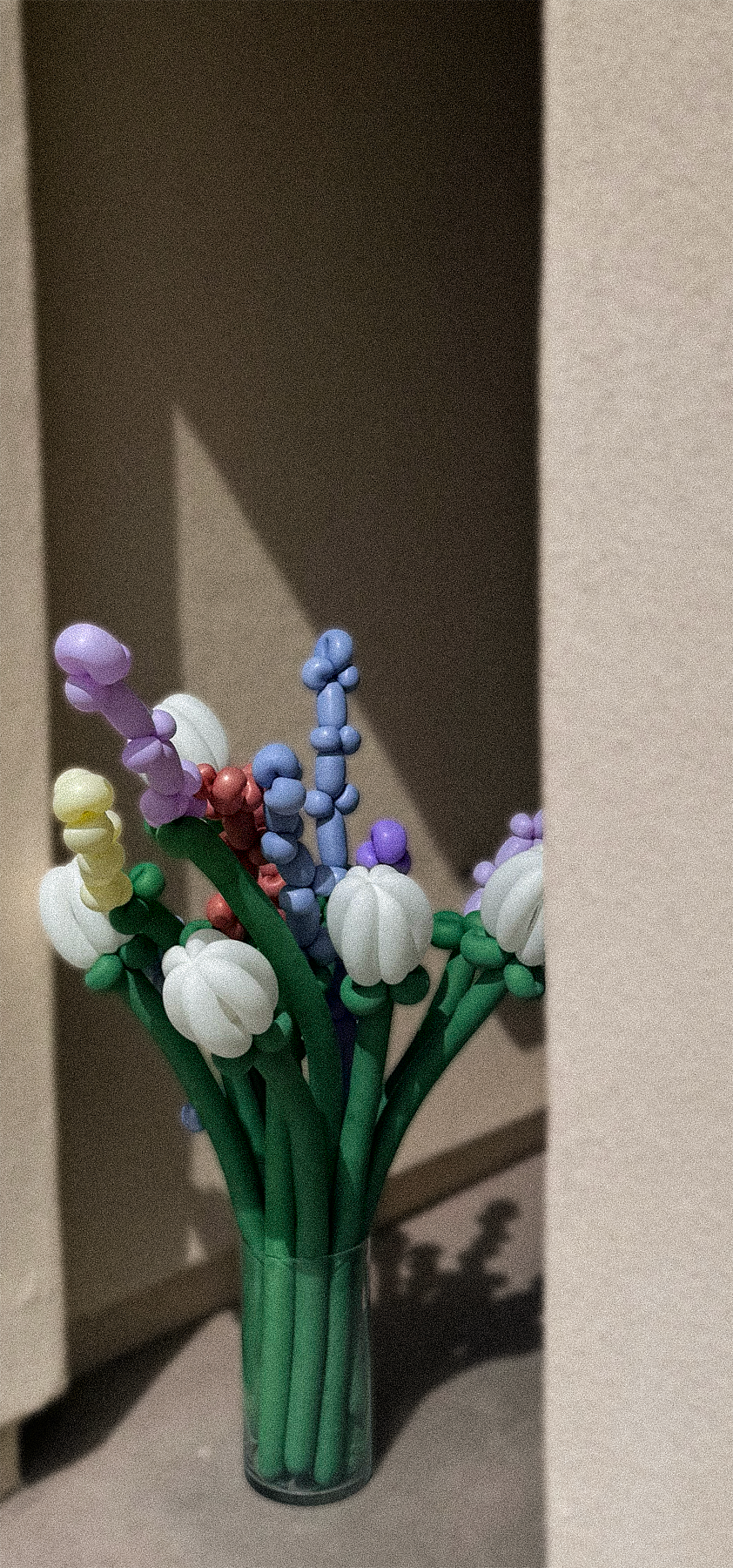 A glass vase filled with colorful artificial flowers made from beads and foam, resembling a bouquet of spring flowers.