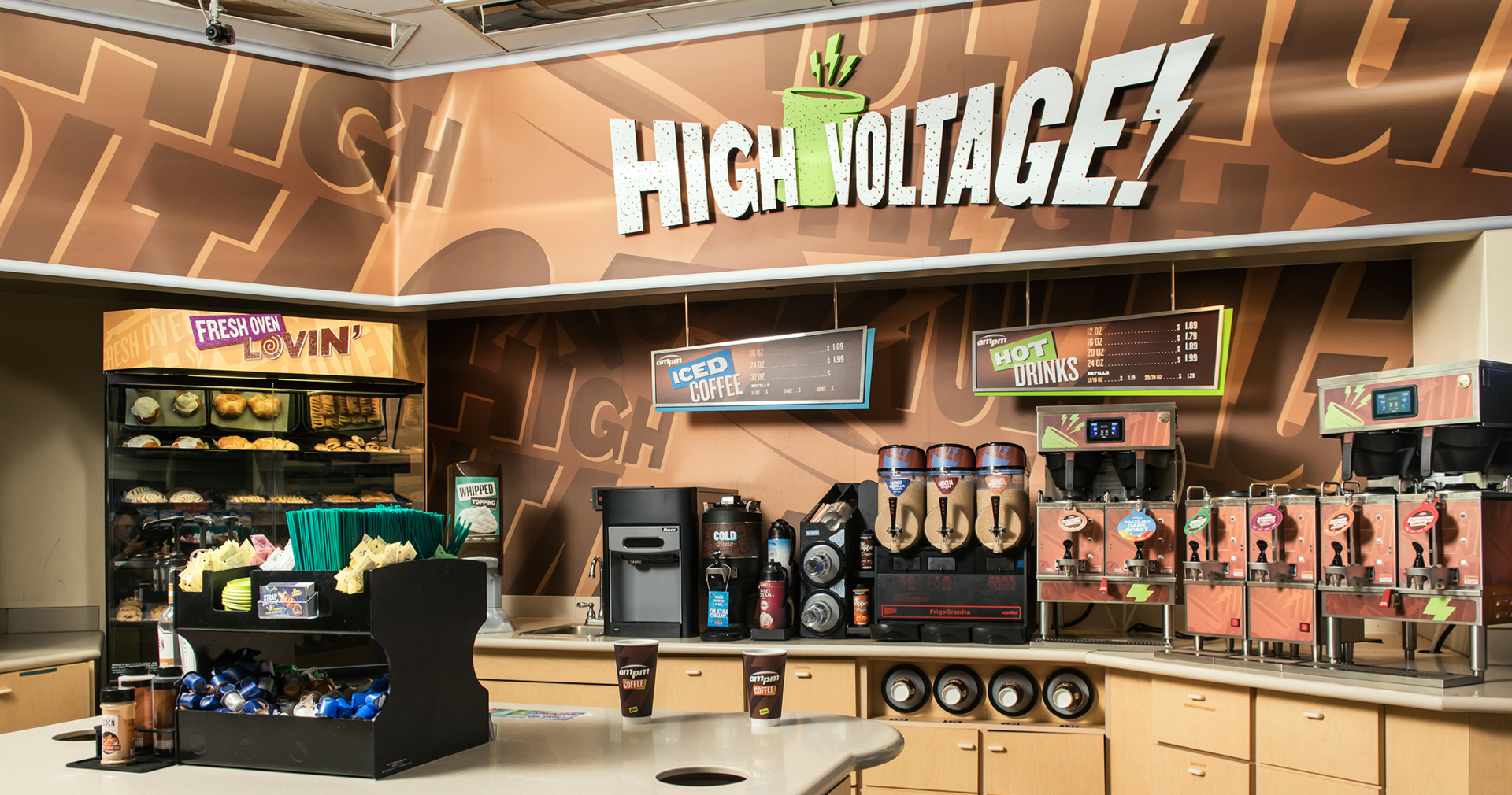 Coffee and beverage station with hot chocolate, iced coffee, hot drinks dispensers, pastries, and snacks in a cafe