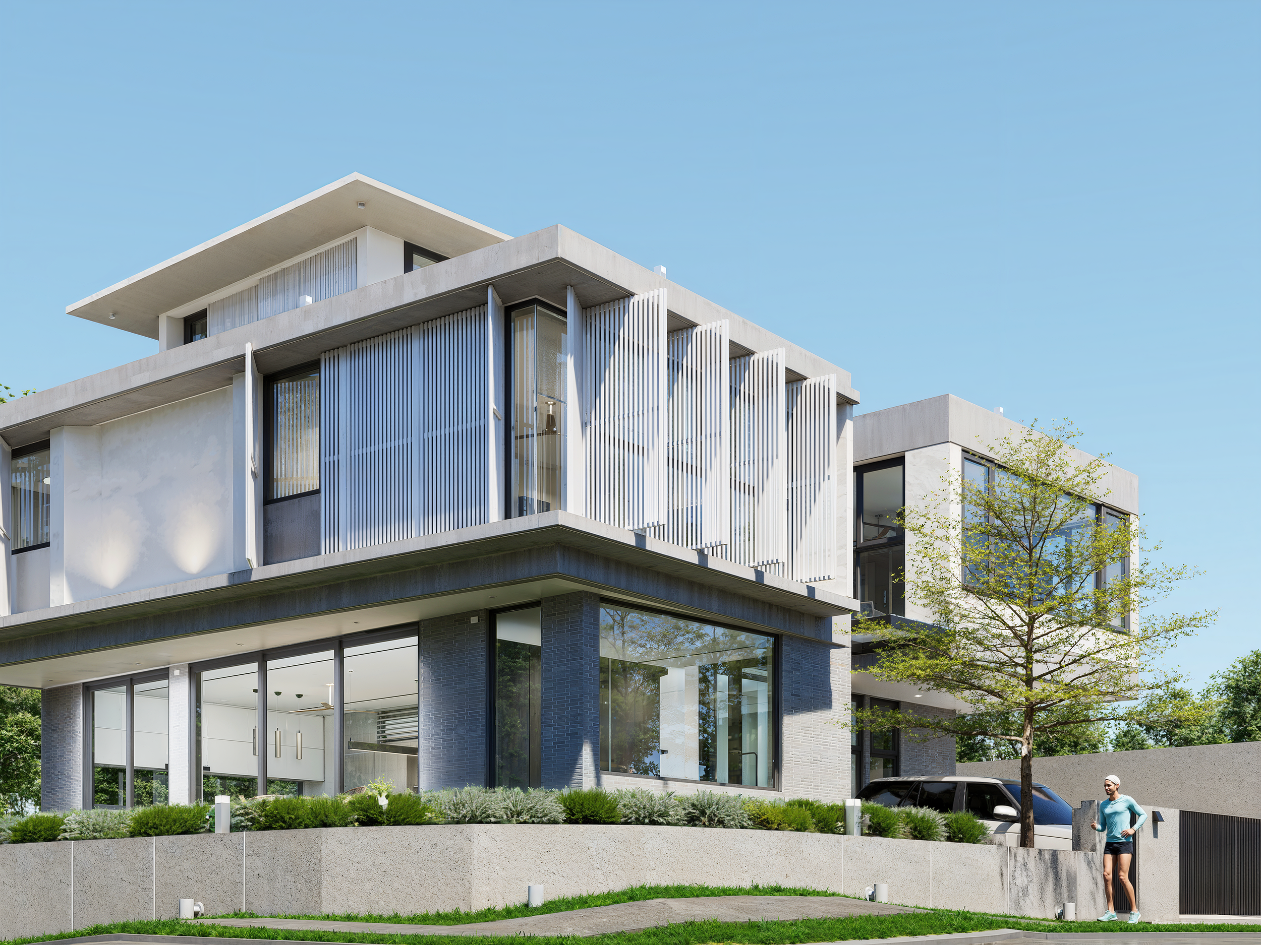 Modern multi-story house with large glass windows, white exterior, vertical white slats, and a landscaped front yard with a woman in athletic clothing standing near a tree.