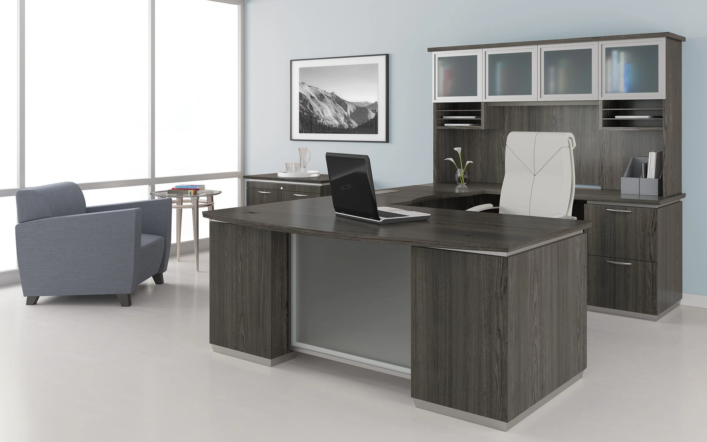 Modern office with a large wooden desk, white leather chair, gray armchair, built-in cabinets, and large windows.