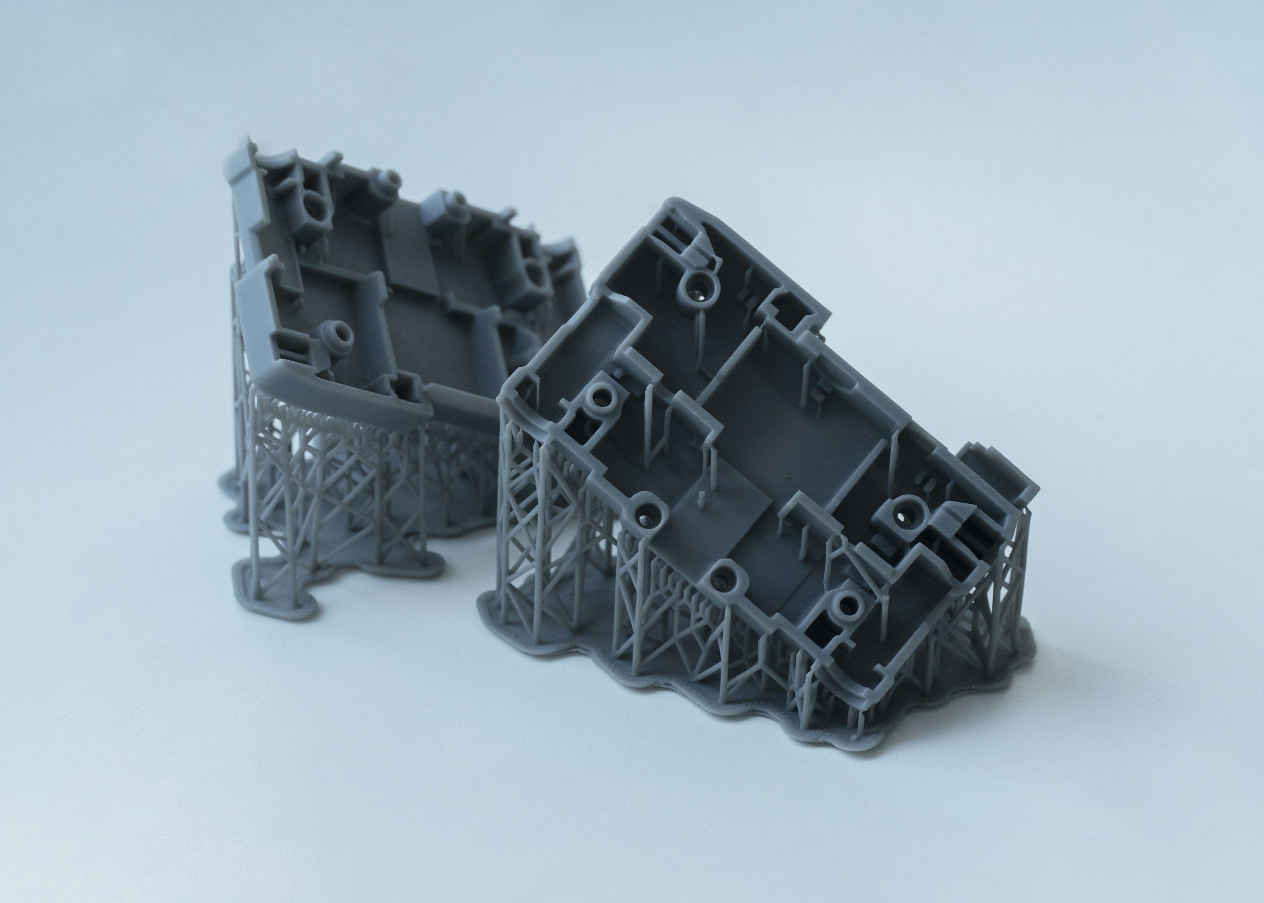 Gray plastic structural components placed on a white background, resting on a wireframe support.