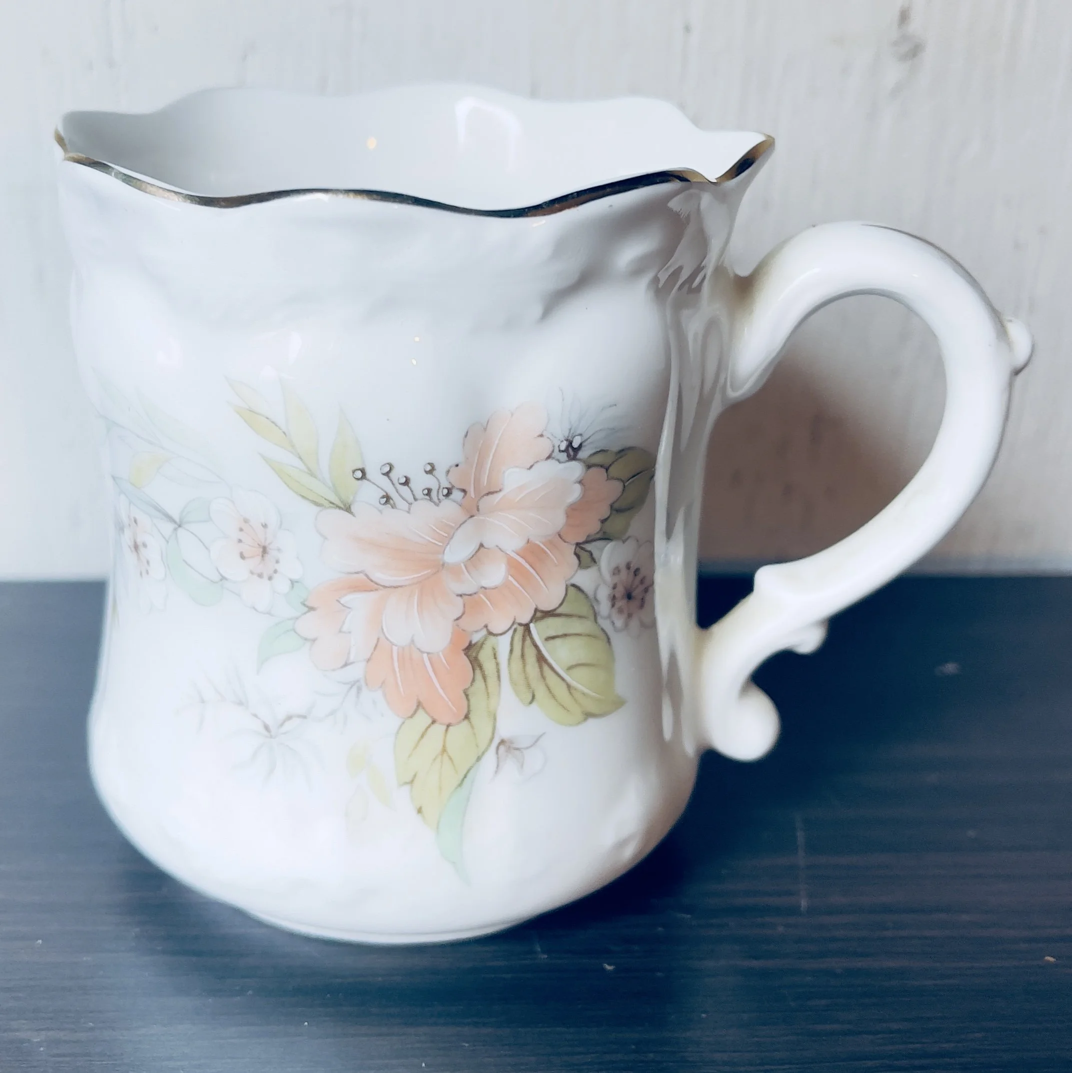 White creamer with flower on it and wavy top