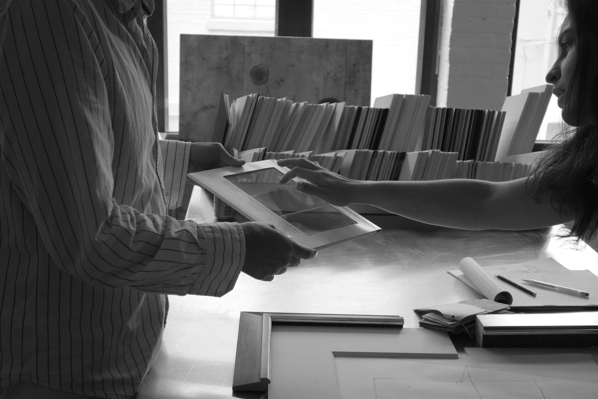 Custom framing consultation in Long Island City showroom — client selecting museum-grade UV glass and conservation matting options
