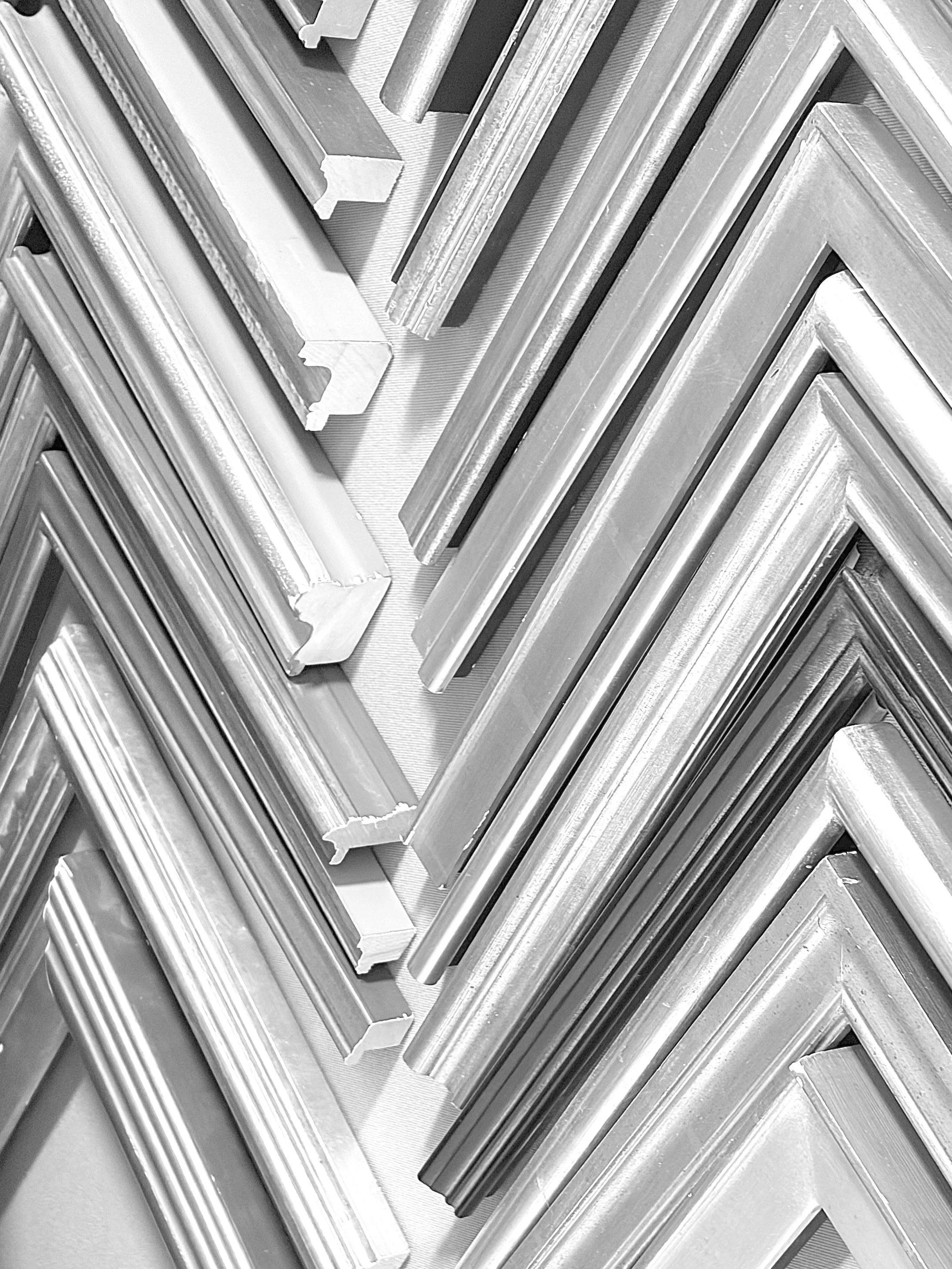 Stacked metallic picture frames with protective plastic corners in a diagonal arrangement.