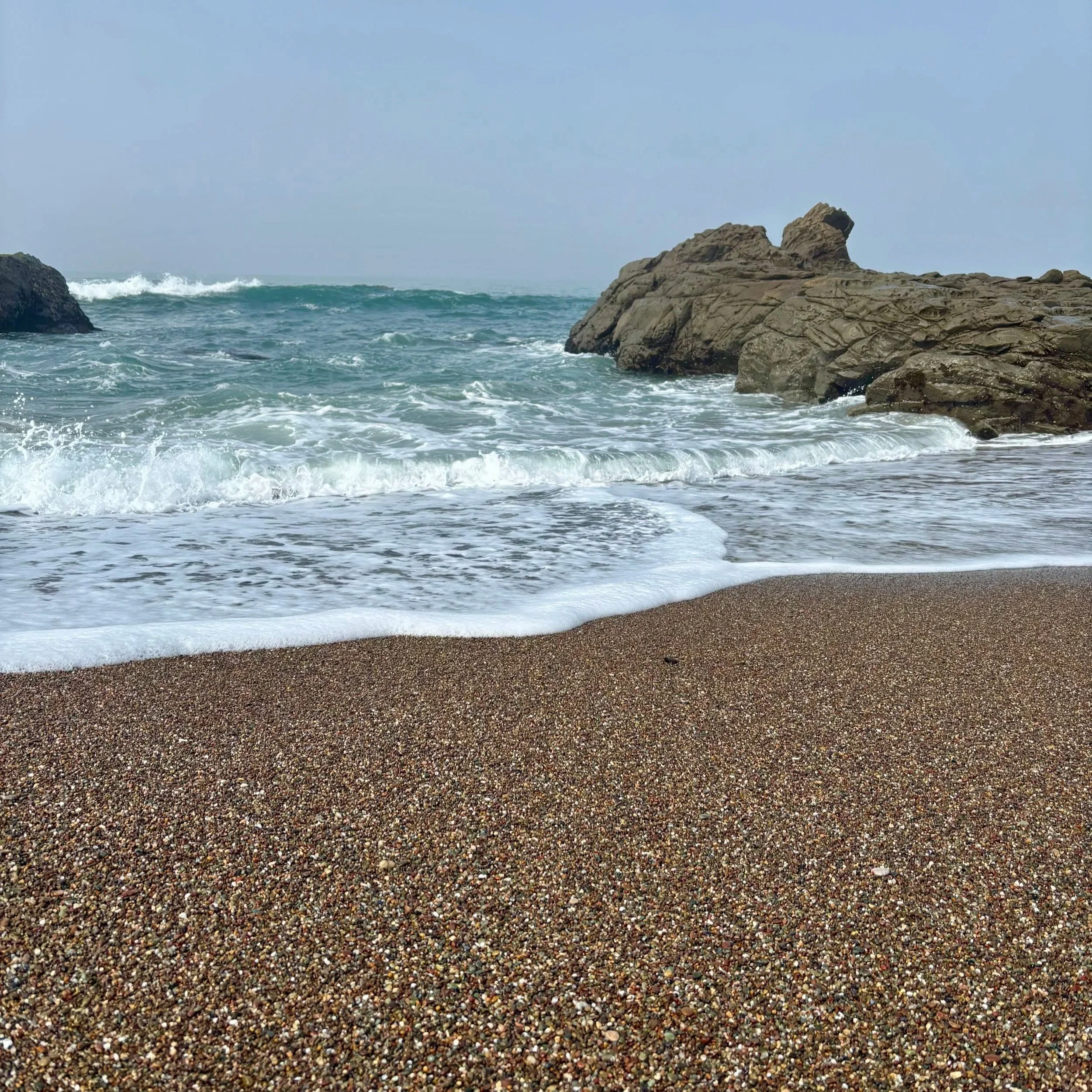 Pebble beach with ocean waves and rocks