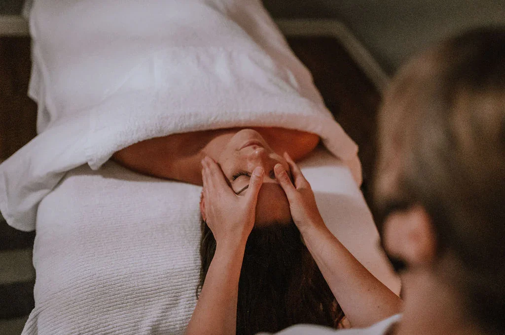 A woman receiving a facial massage from a beauty therapist in a spa.