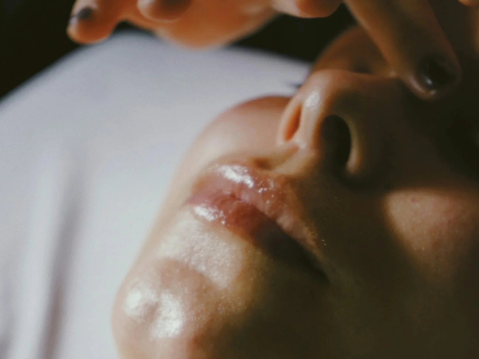 Close-up of a person's face with their eyes closed, highlighting their nose and lips.