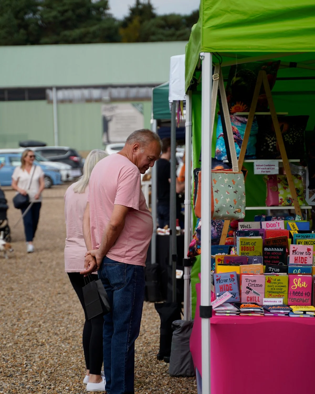 People browsing books and accessories at an outdoor market stall.