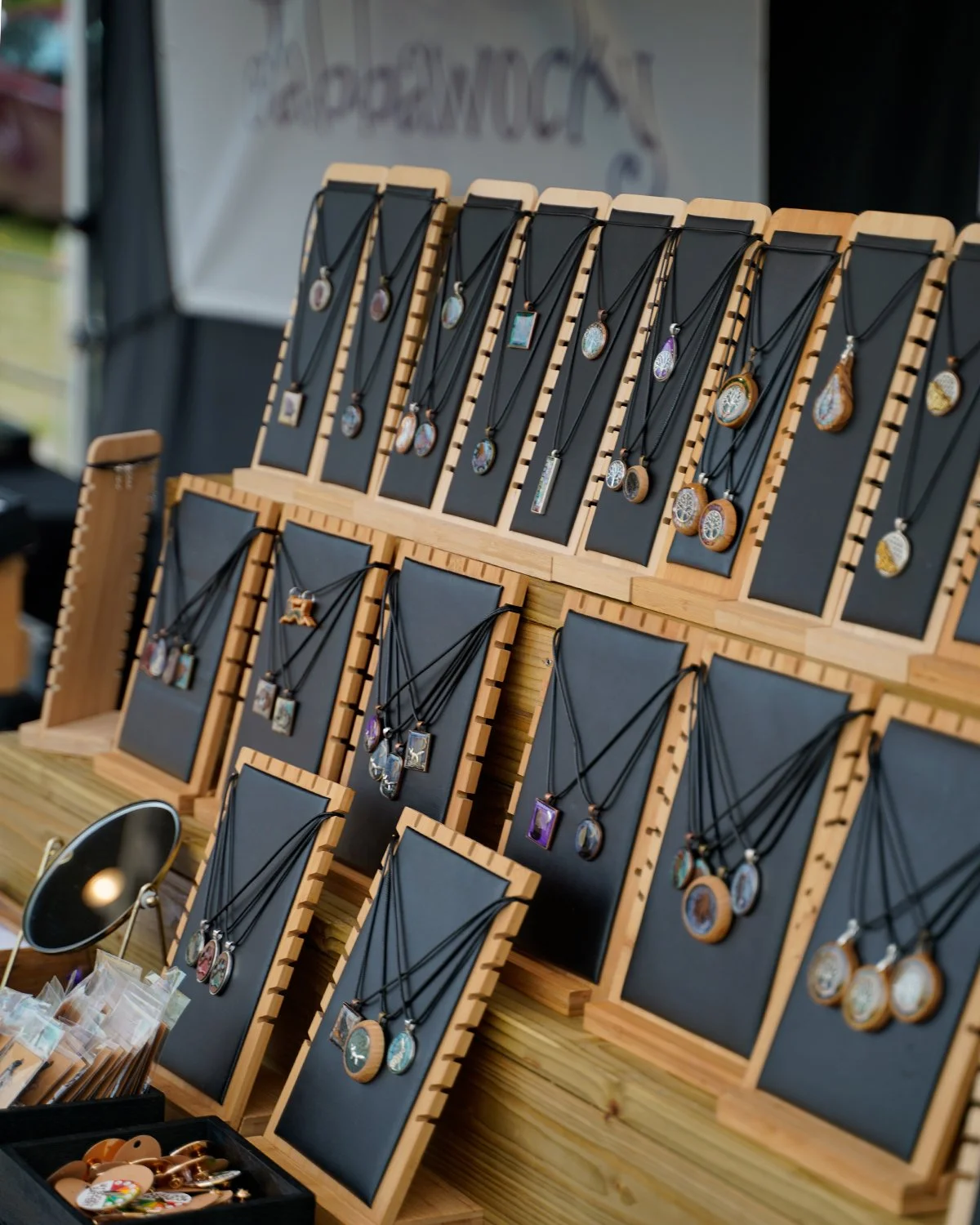 Display of various necklaces with colorful pendants hanging on black cards at a market stall.