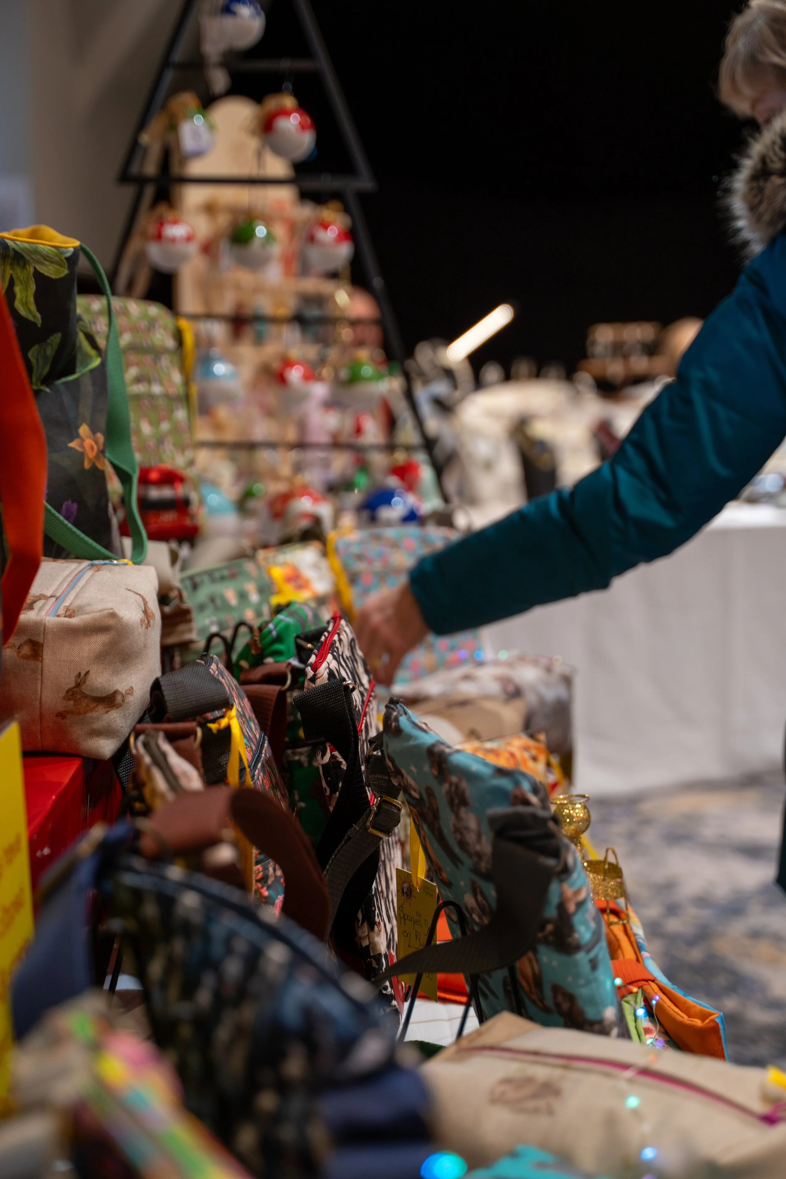 Display of colorful woven and fabric backpacks and bags at a market stall.