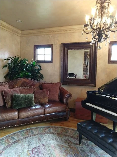 A large scale planter thoughtfully positioned behind the sofa in a grand piano living room, adding height, softness, and a natural focus point to the space.
