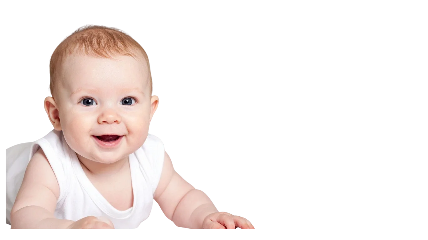 Smiling baby with light skin, red hair, and blue eyes wearing a white sleeveless shirt, lying on stomach against a black background.