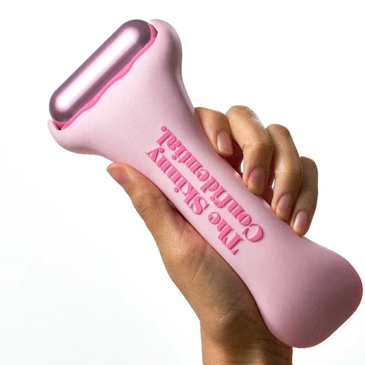 A pink skin care device labeled 'The Slimy Cowgirl' being held in hand.