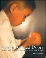 A young boy holding a glowing orange object in his hands, looking at it intently.