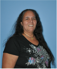 A woman with long dark hair wearing a black T-shirt with a colorful floral design, smiling against a blue background.