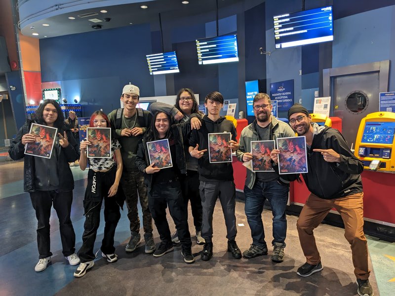 Group of seven young people at an airport, holding posters and making gestures, with flight information screens and self-service kiosks in the background.
