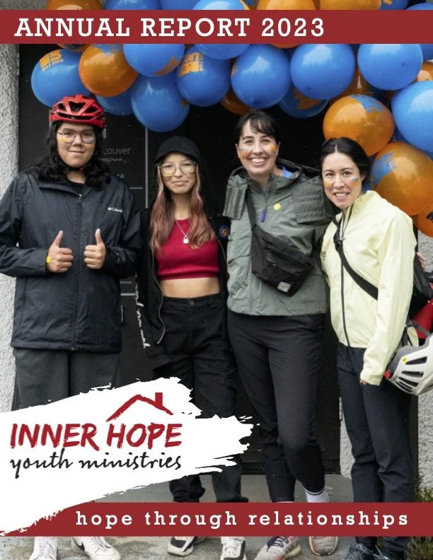 Group of four women standing outdoors in front of a balloon arch, smiling, with an 'Inner Hope youth ministries' sign and 'Annual Report 2023' banner.