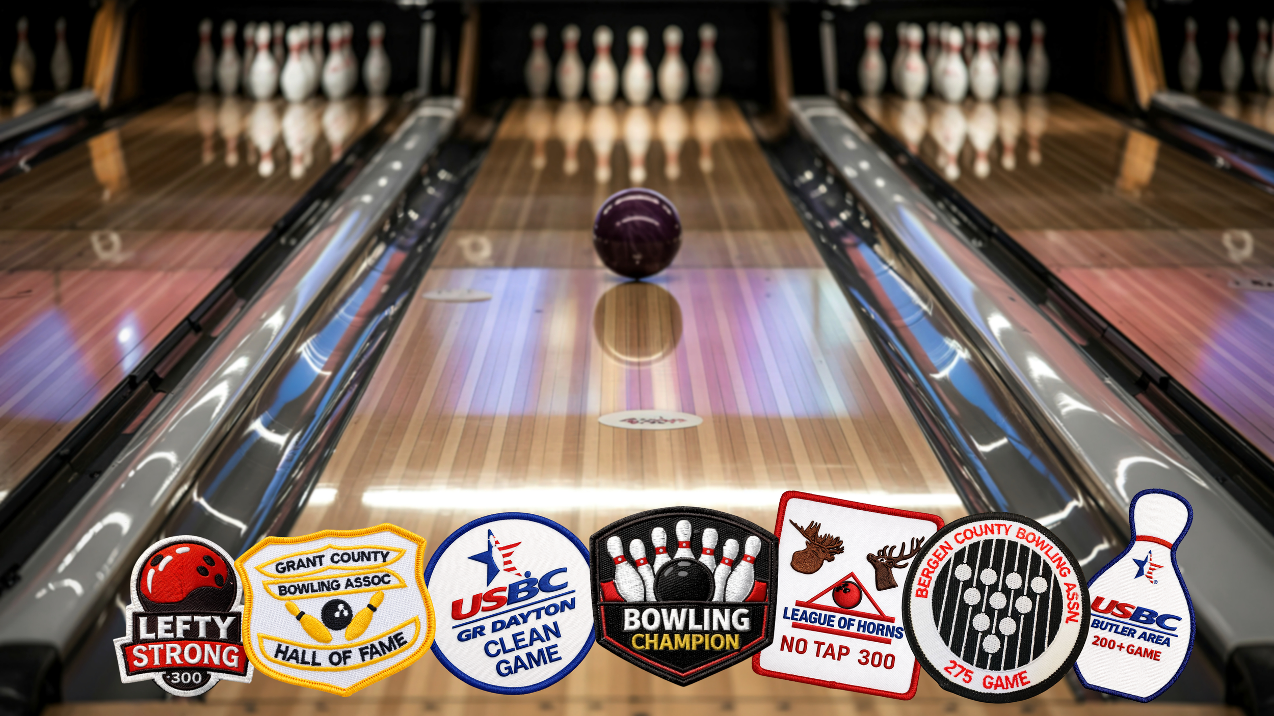 A bowling alley with a purple bowling ball on the lane, multiple pins set up at the end, and several promotional patches at the bottom featuring bowling team logos and honors.