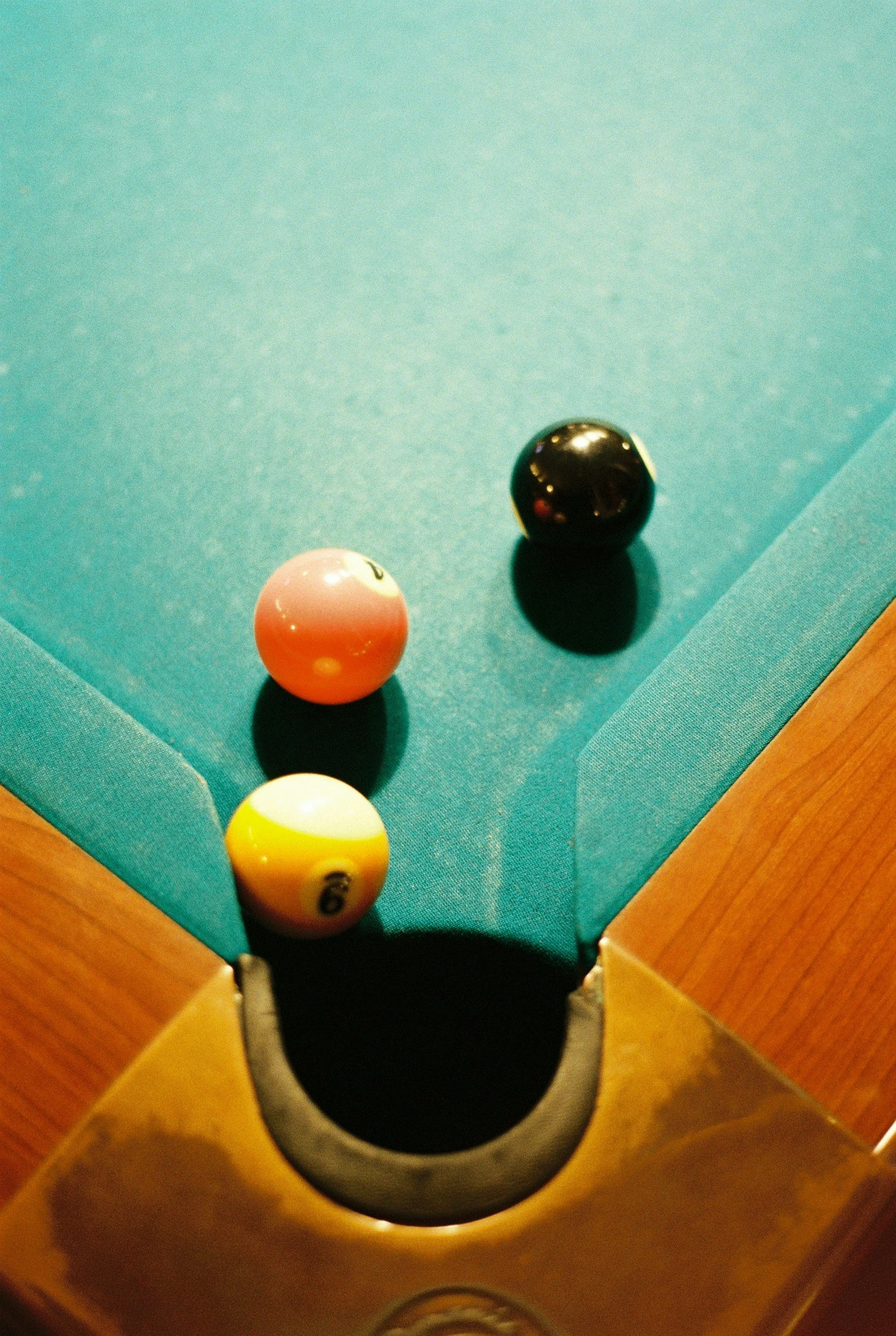 Three billiard balls placed on the green felt of a pool table near the corner pocket.