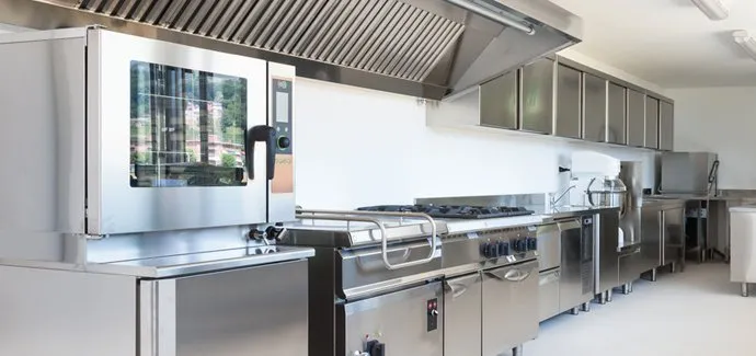 A commercial kitchen with stainless steel appliances, including an oven, stove, and storage cabinets.