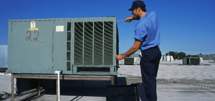 Technician servicing an HVAC unit on a rooftop.