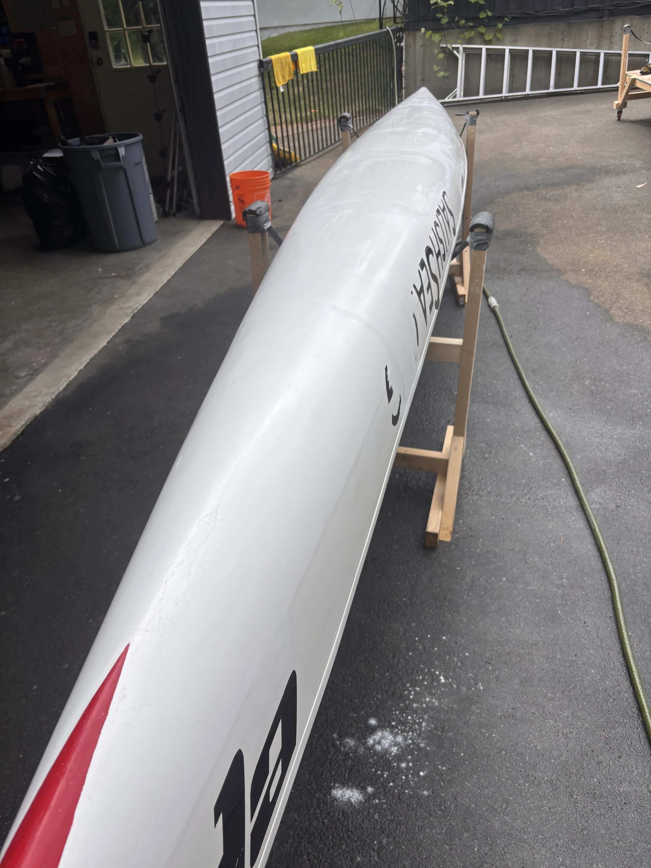 A large rocket or missile placed on wooden supports in a driveway, with part of a house and garage visible in the background, and snow or ice on the ground.