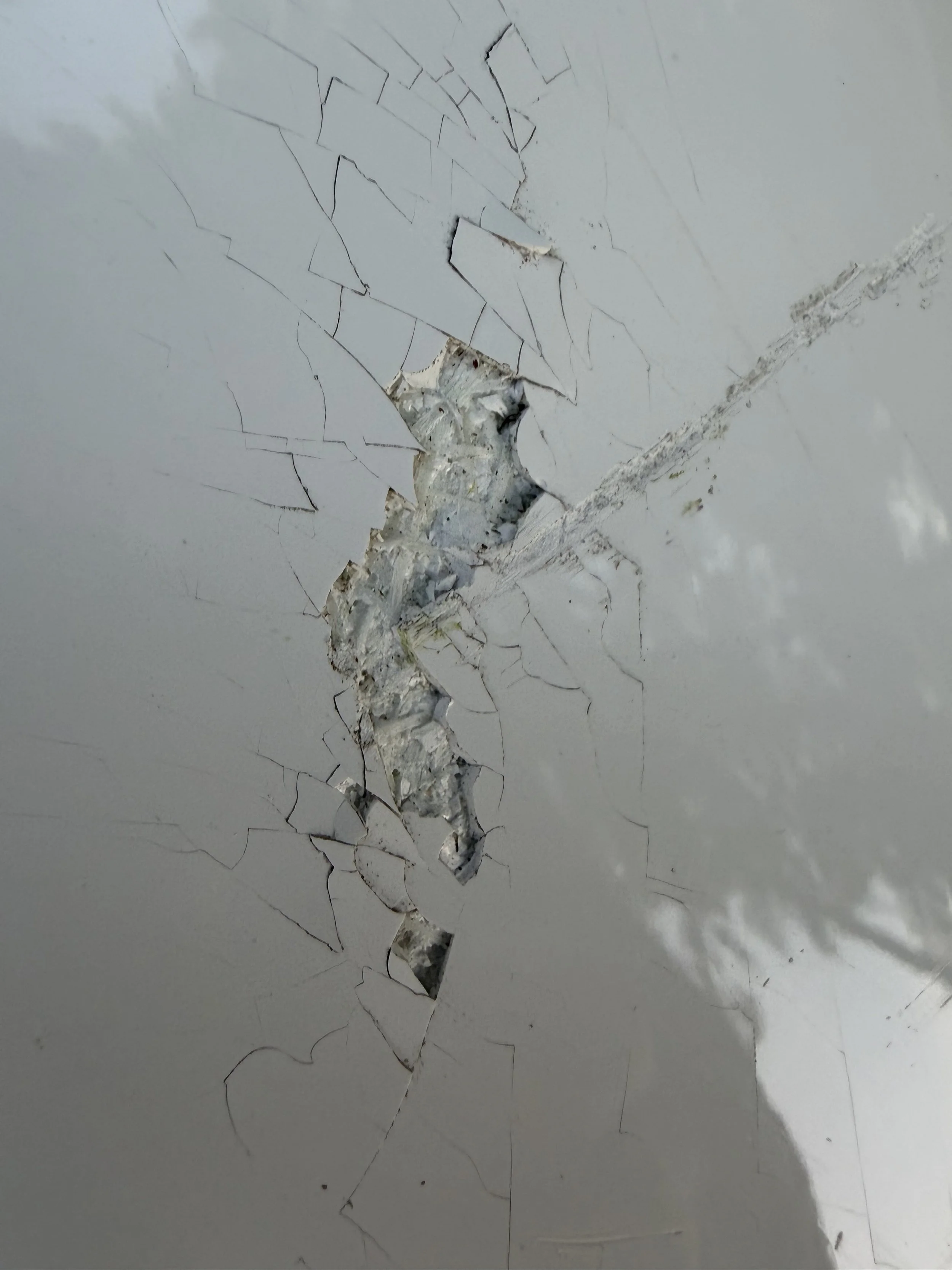 Close-up of a cracked and peeling white painted ceiling.