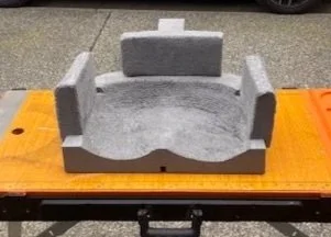 Grey foam or Styrofoam mold with side supports, placed on a wooden table outdoors.