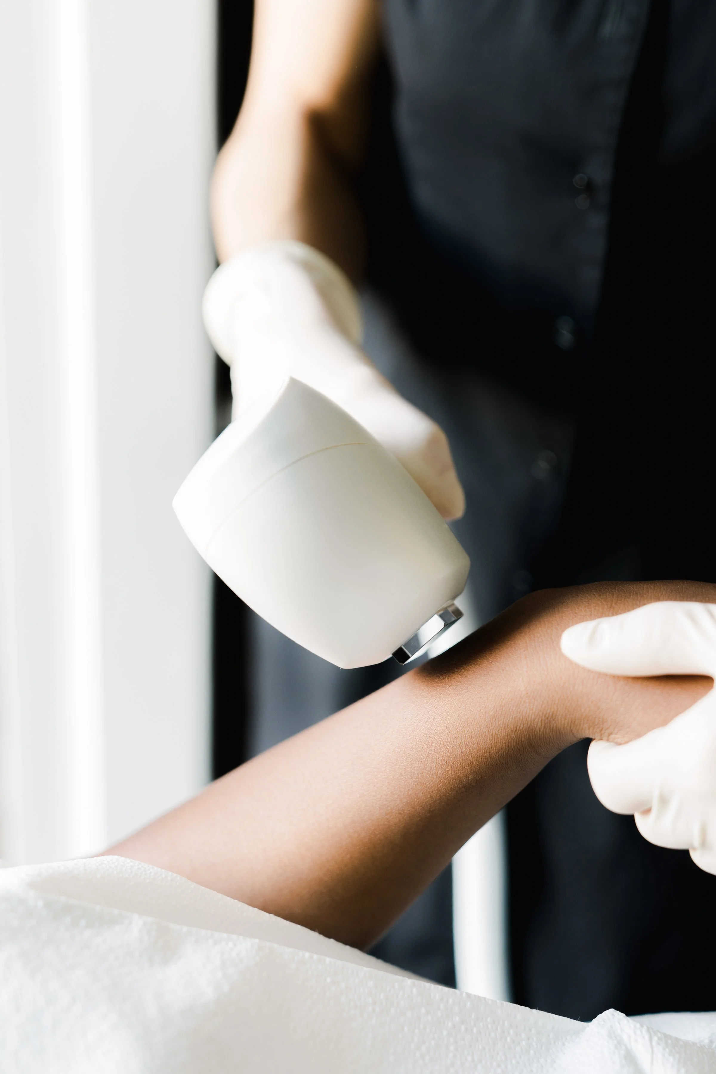 Medical professional using a handheld device to examine a patient's arm.