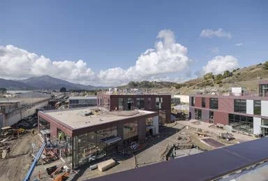 Under construction buildings in a hilly area with a cloudy sky in the background.