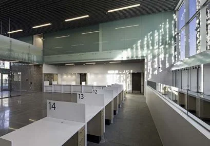 Empty airport or train station waiting area with numbered desks 14 to 12, large windows, and modern design.
