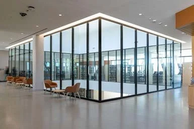 Modern indoor space with large glass windows and orange chairs.