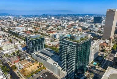A cityscape with tall modern buildings and a clear blue sky.
