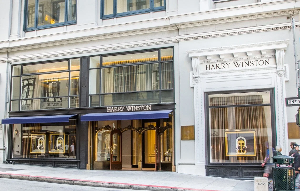 Harry Winston jewelry store on a city street with large display windows and ornate facade.