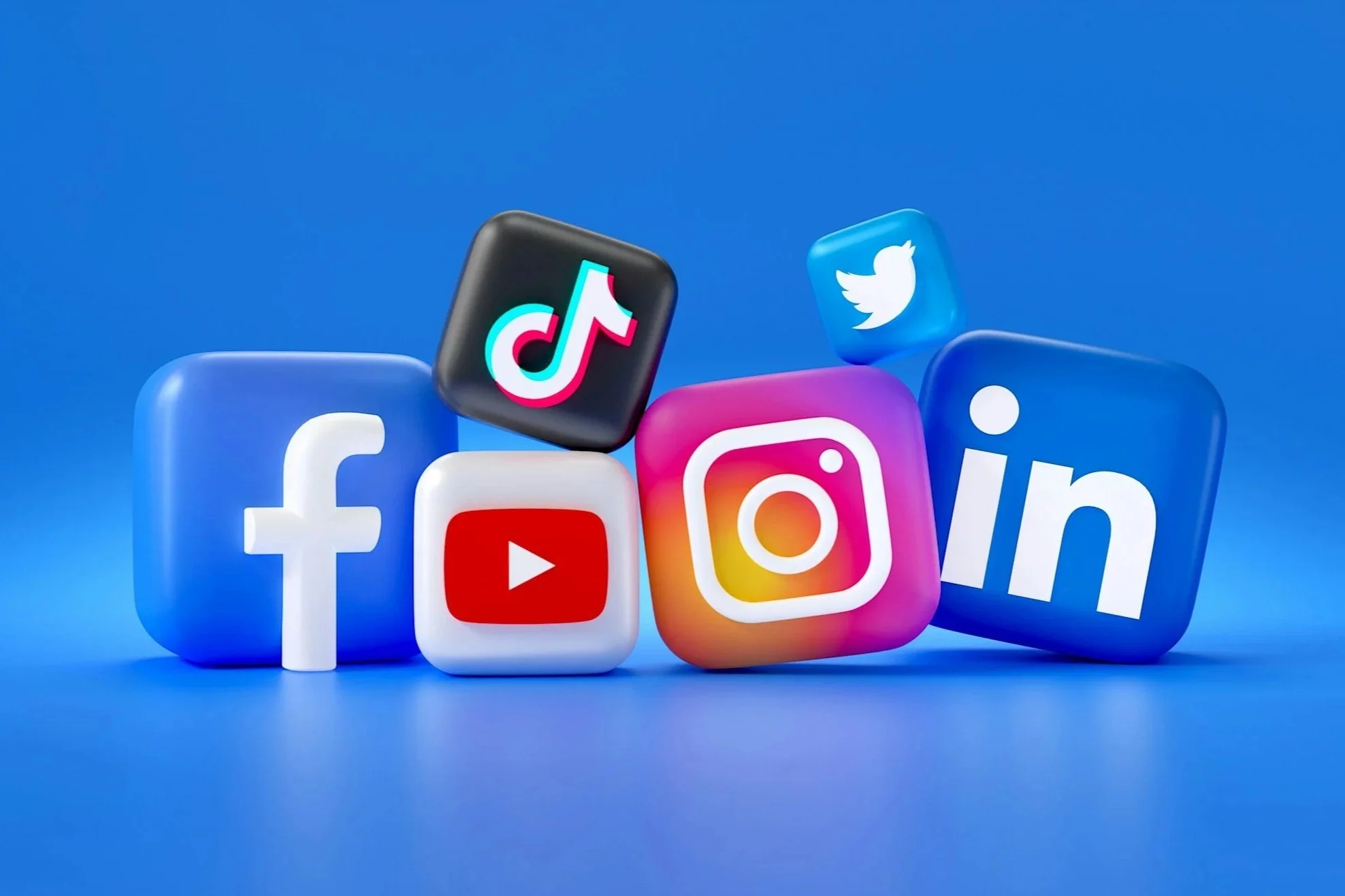 Collection of social media app icons, including Facebook, YouTube, TikTok, Instagram, Twitter, and LinkedIn, displayed as 3D blocks on a blue background.