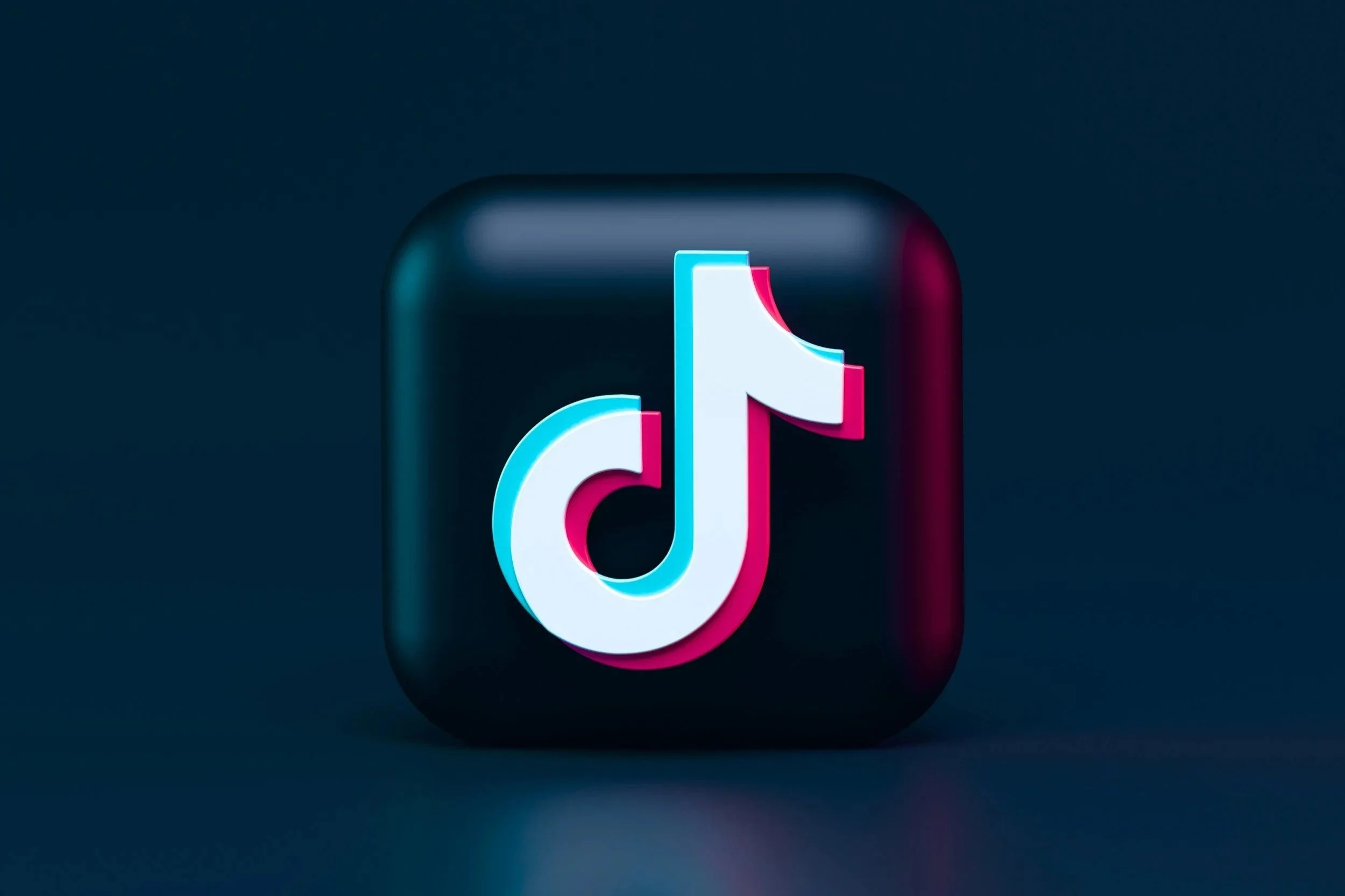 TikTok app icon with a black rounded square background and a stylized music note in the center, illuminated with pink and blue neon lighting.