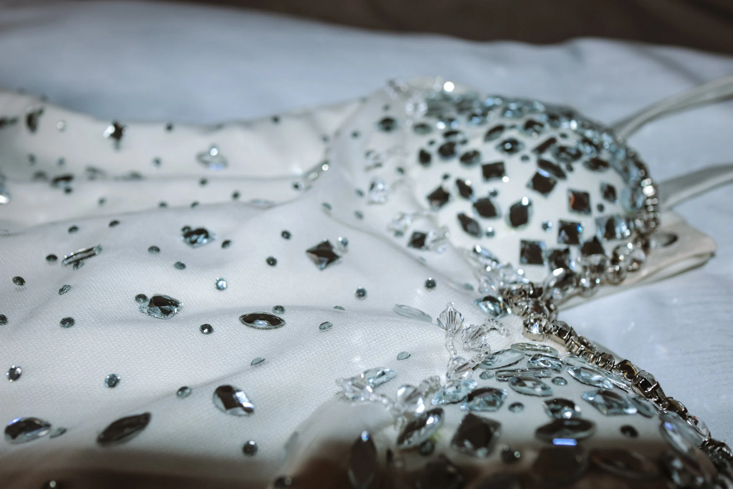 Close-up of white fabric adorned with black and clear rhinestones, with a circular rhinestone embellishment.