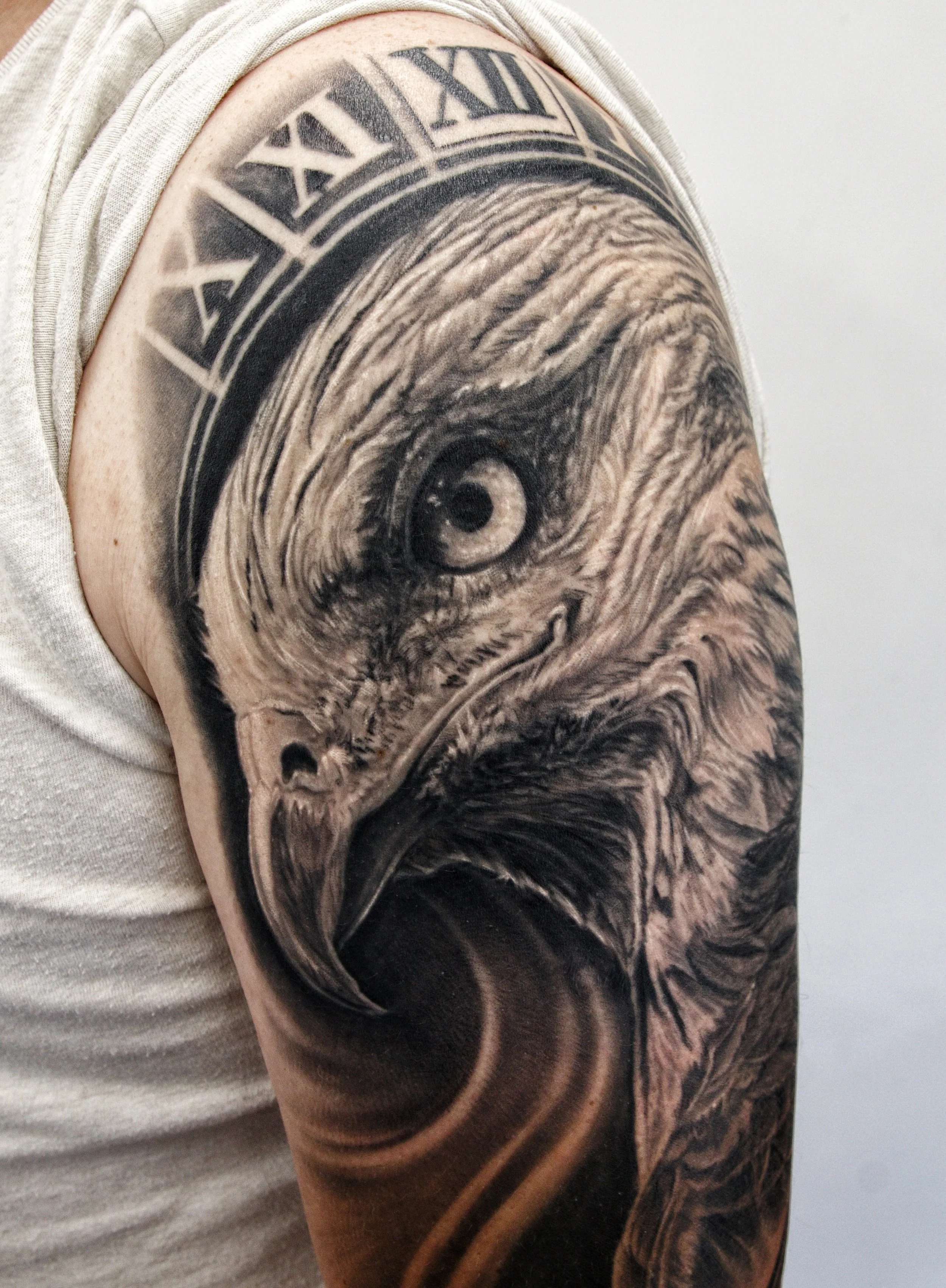 Close-up of a person's shoulder tattoo featuring a woodgrain design and a black and white clock with Roman numerals.