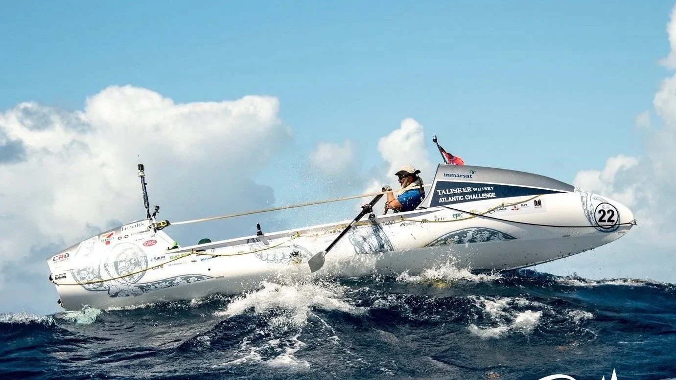 Ocean rowing boat 'The Kraken' cresting a large wave as the rower battles the sea conditions
