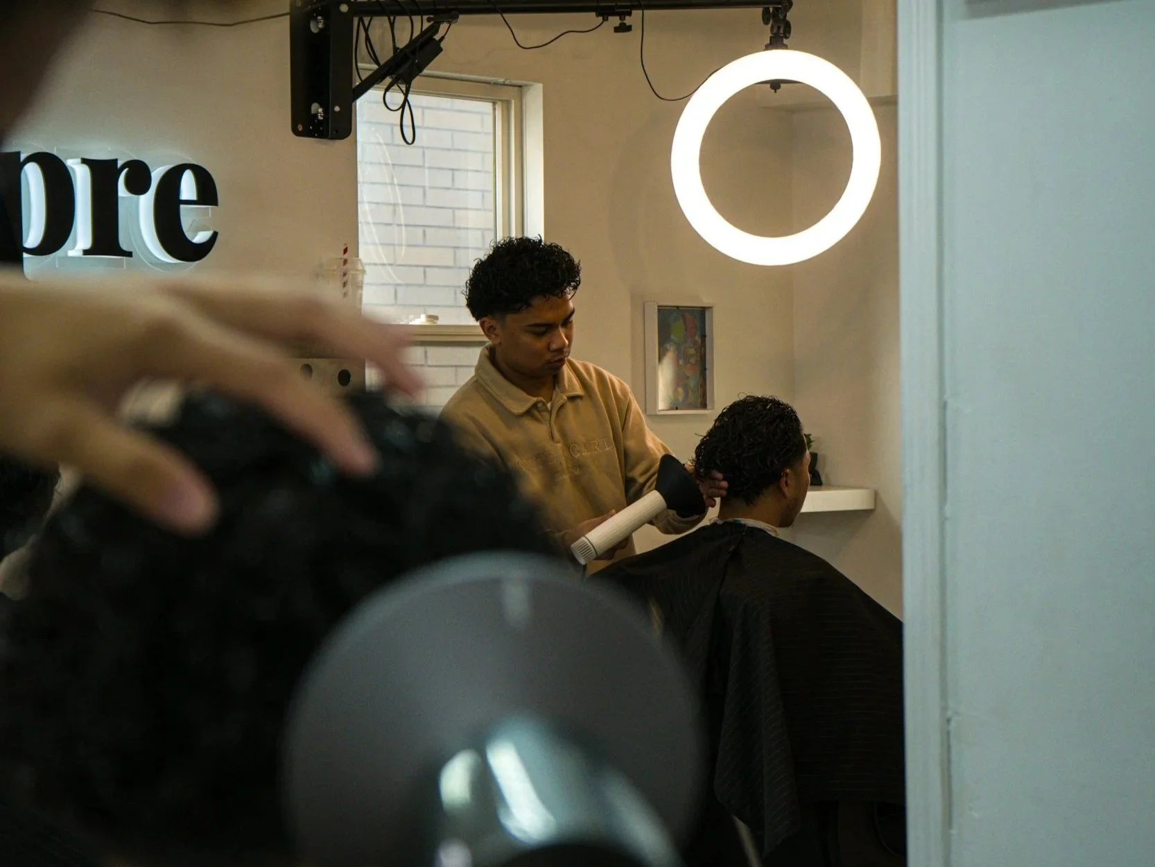 A hairstylist blow-drying a woman's hair in a salon.