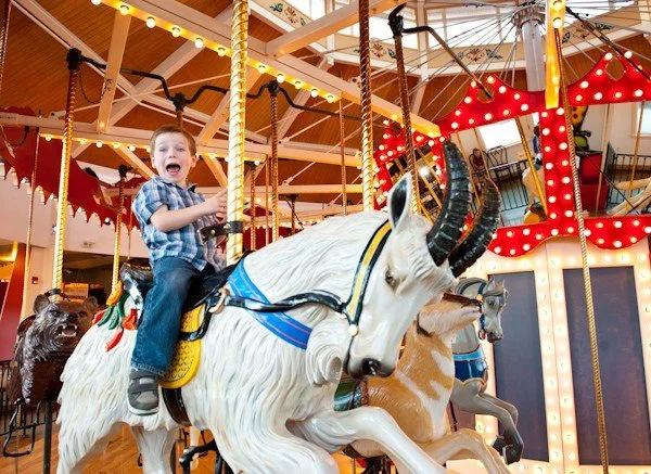 A young boy riding a carousel unicorn at an carousel.