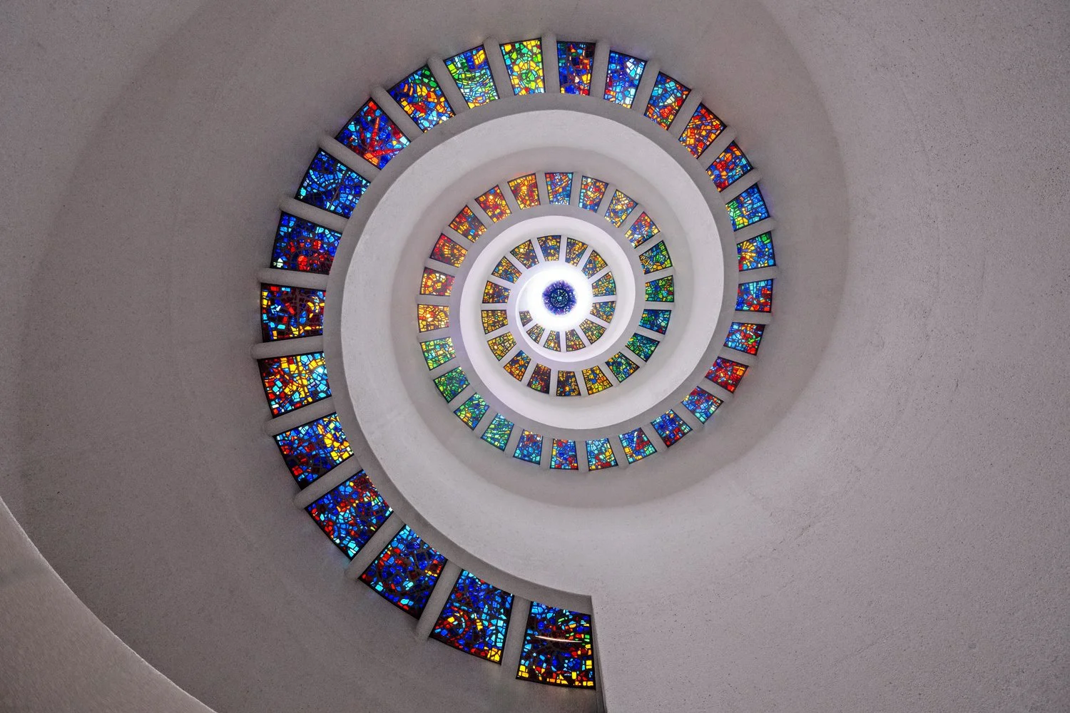Colorful spiral stained glass window in a church ceiling.