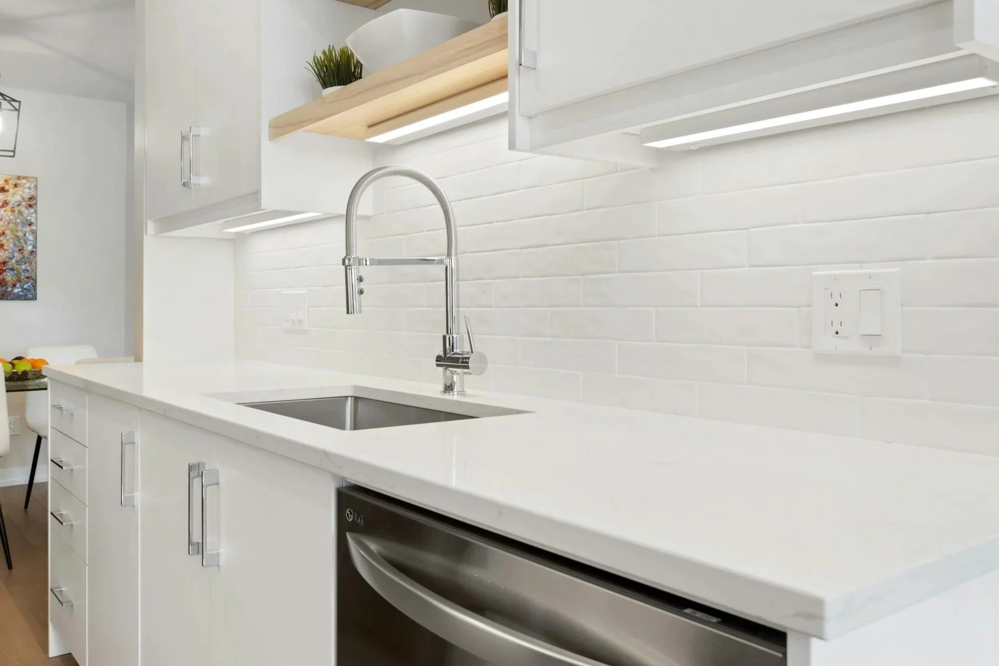 Modern kitchen with white cabinets, a white countertop, a stainless steel sink, a chrome faucet, and white subway tile backsplash.