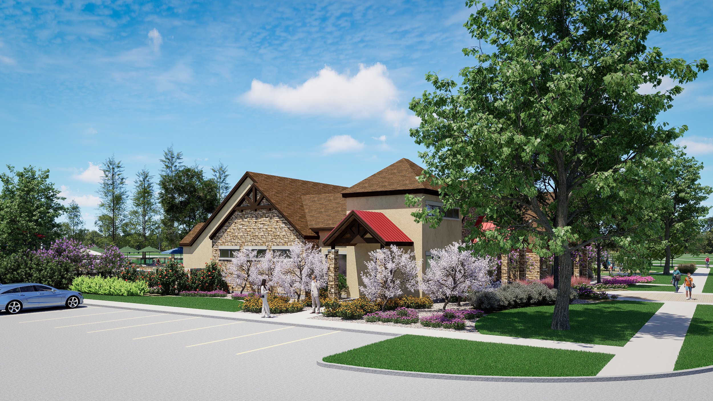 A modern residential building with a parking lot in the foreground, surrounded by lush greenery, flowering trees, and a landscaped garden, under a blue sky with scattered clouds.
