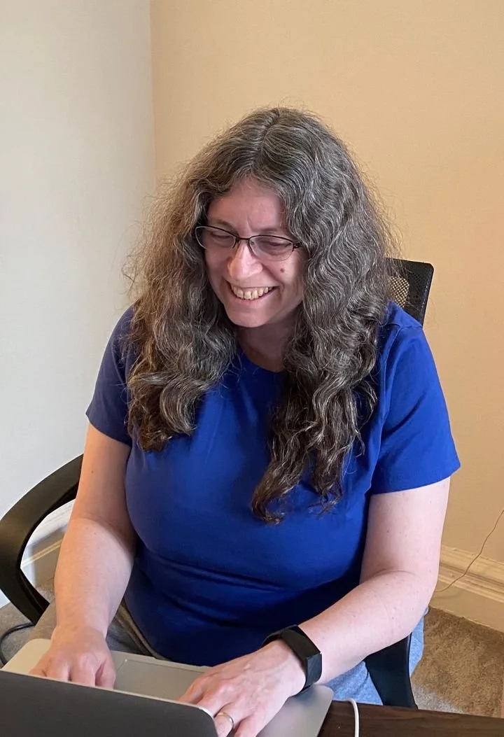 Karen Bromberg at her desk, smiling at her laptop