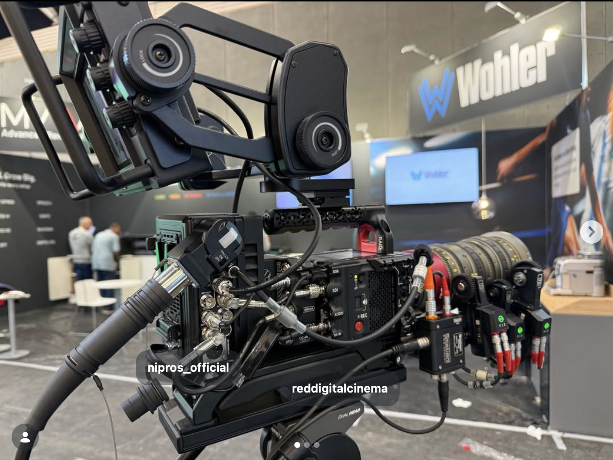 Close-up view of a professional digital cinema camera setup with various cables and attachments, displayed at an exhibition booth with 'Wahler' branding in the background.