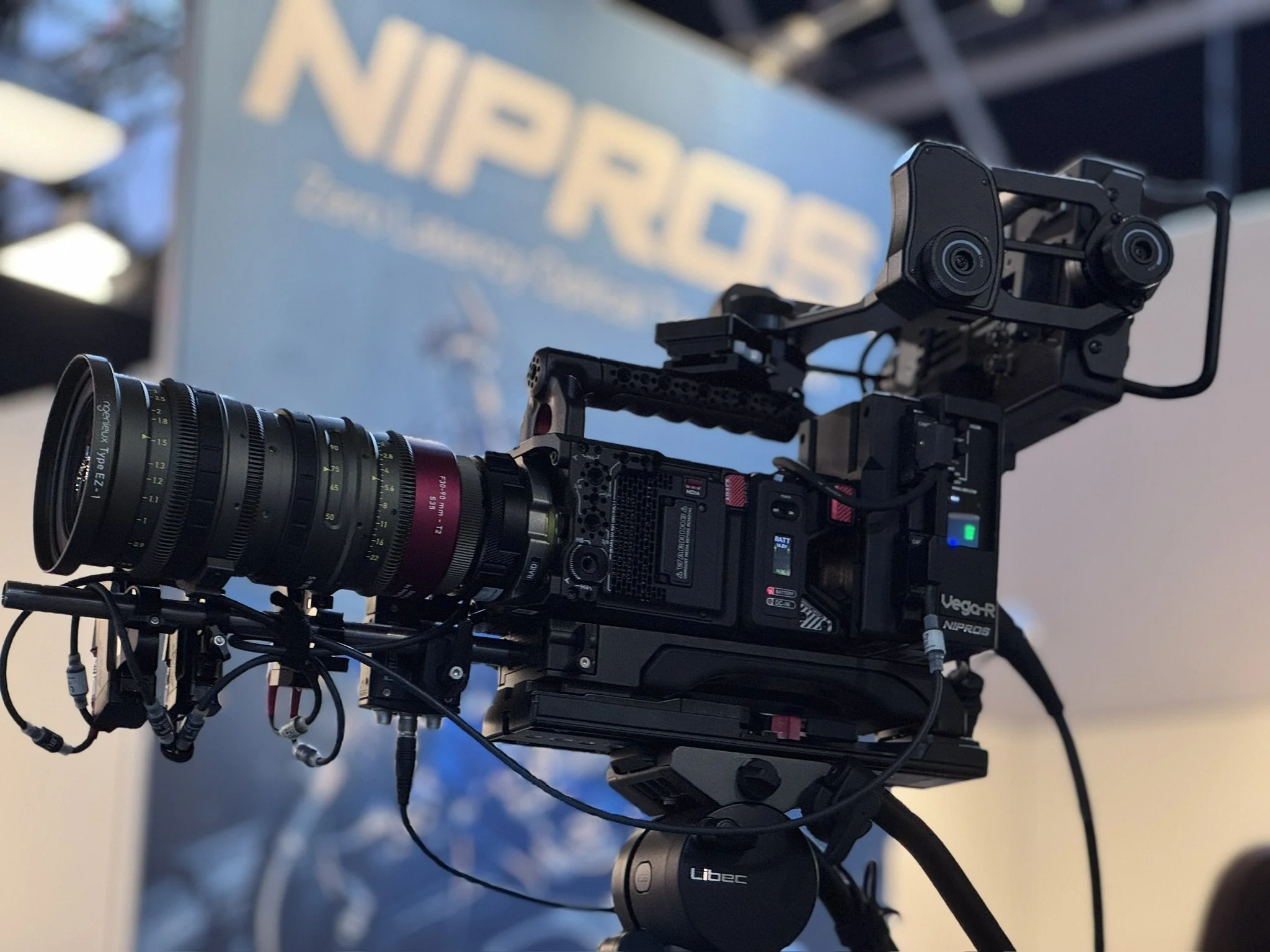 Close-up of a professional camera equipped with a zoom lens, mounted on a sturdy rig with various cables connected, used for filming or video production.