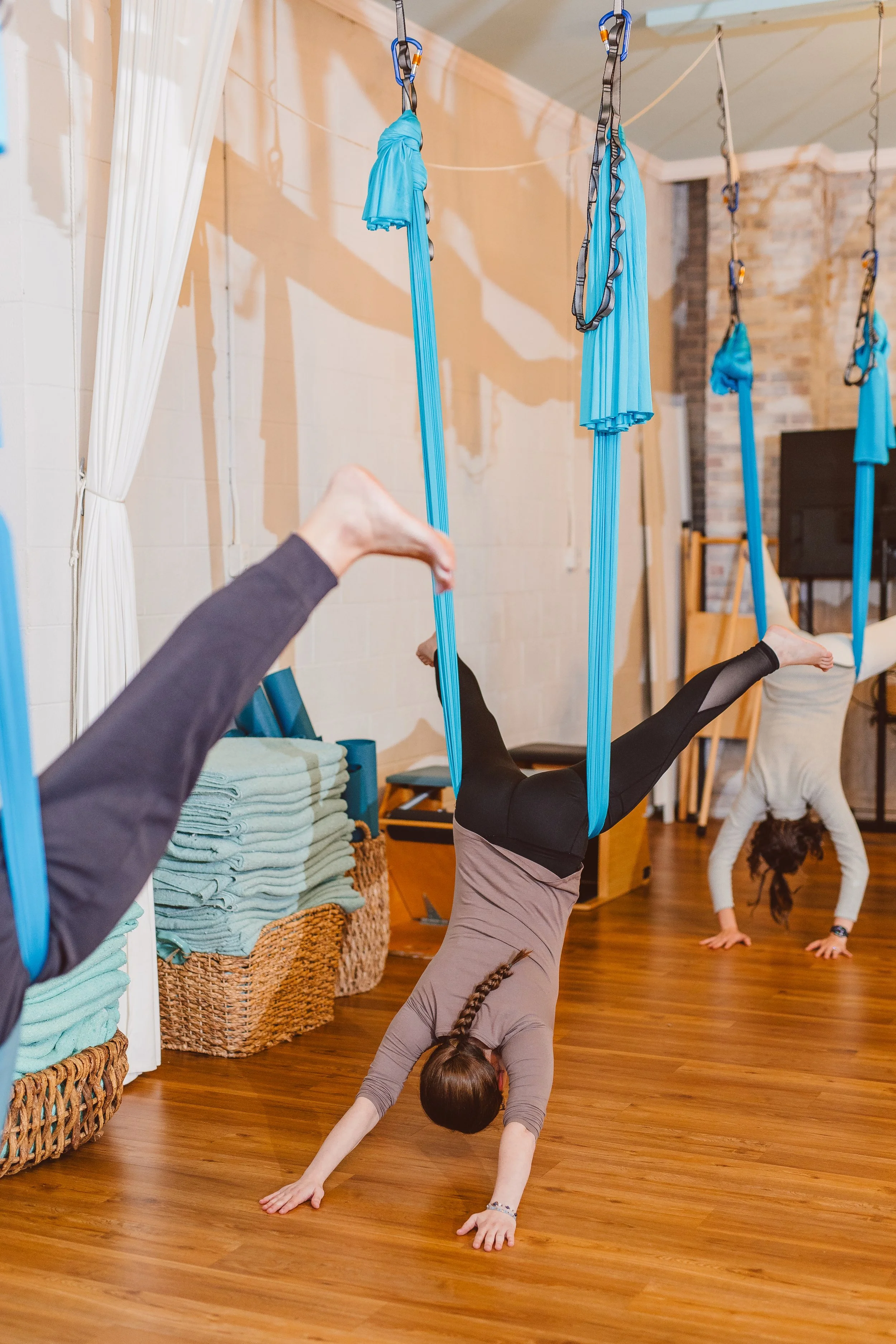 Aerial yoga class at Coastal Retreat Studios in Easton, MD — clients exploring inversion and decompression in fabric hammocks